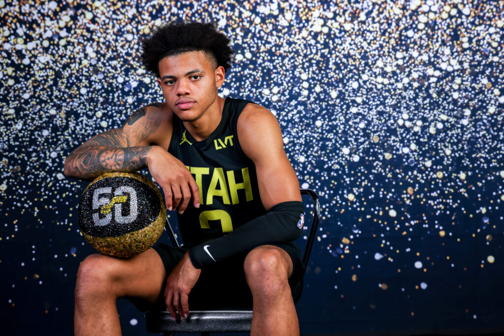 Keyonte George portrait during Utah Jazz NBA Media Day holding a basketball under colored studio lighting.