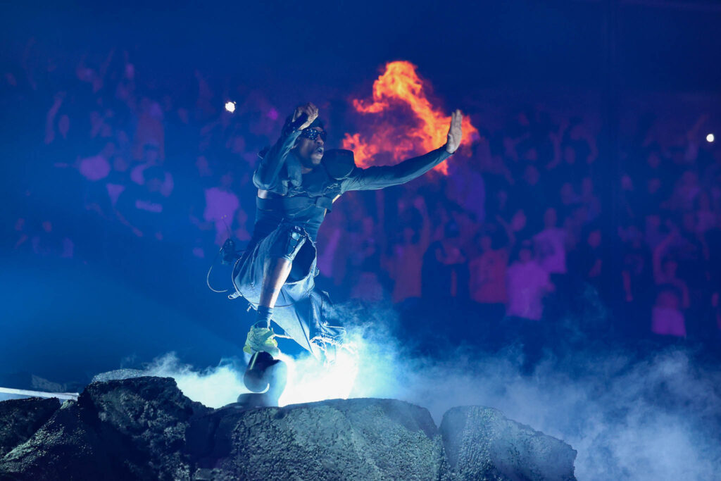 Travis Scott performing live in concert during a high-energy hip hop stage performance