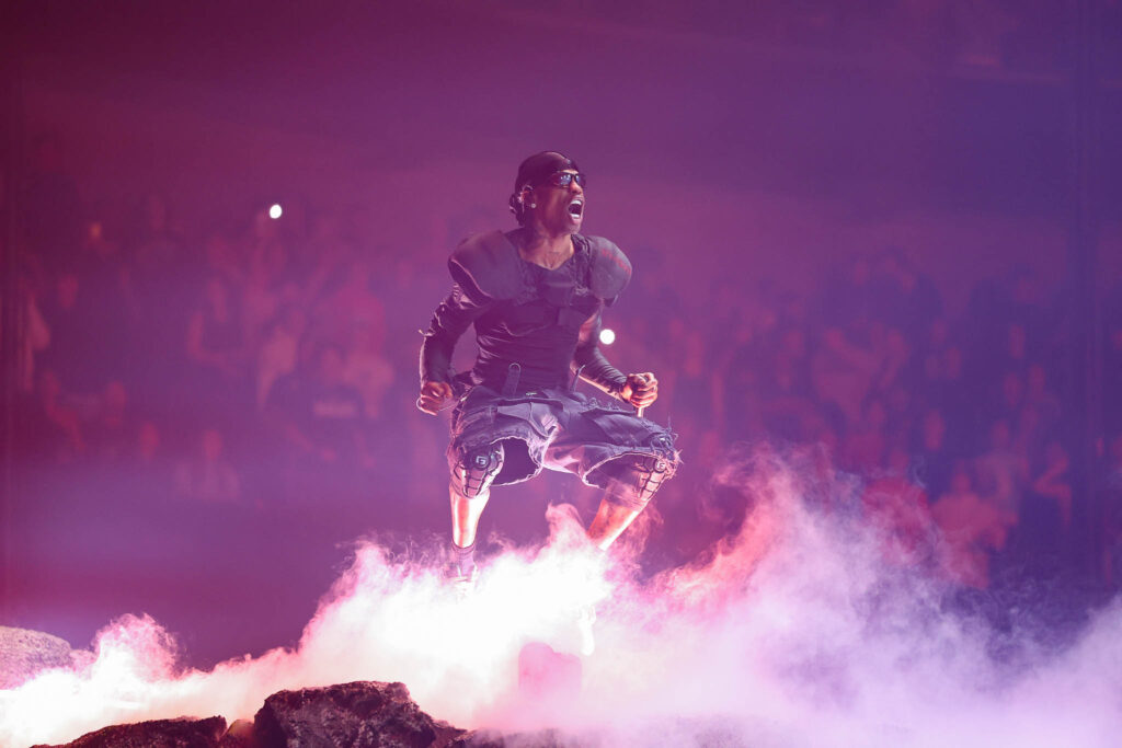 Travis Scott performing live in concert during a high-energy hip hop stage performance