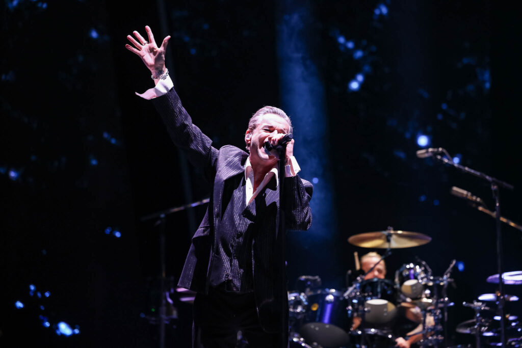 Depeche Mode live concert performance with dramatic stage lighting and crowd atmosphere