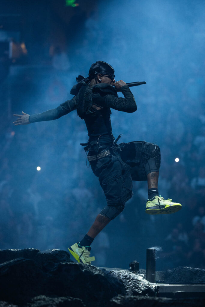 Travis Scott performing live in concert during a high-energy hip hop stage performance