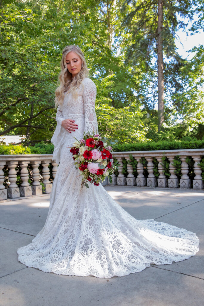 Bride in lace wedding dress holding a bouquet during an outdoor bridal portrait photographed by Melissa Majchrzak.